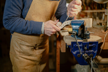 Luthier crafting violin scroll using gouge and vise in workshop