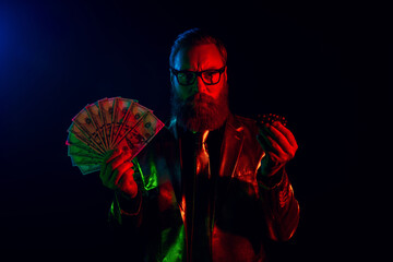 Stylish man in a glossy suit holding cash and poker chips in neon lights, creating a retro vibe