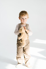 Boy child is holding a stuffed animal, possibly a teddy bear, and appears to be sad