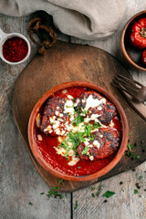 Beef patties in tomato sauce with cheese and herbs, served in a ceramic bowl. Minced meat cutlets, top view