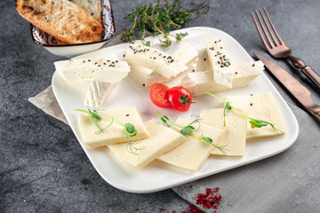 Homemade goat cheese cut into pieces on a white plate. Serbian traditional cheese