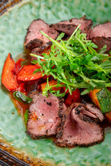 Warm salad with roast beef and stewed vegetables on a plate