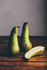 Whole and Halved Conference Pears on Wooden Table