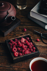 Fresh raspberries in a wooden box and a cup of tea