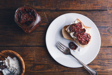 Toasts with cream cheese and sundried tomatoes on a white plate