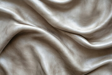 Soft, luxurious, metallic taupe leather draped in elegant folds, showcasing its texture and sheen.