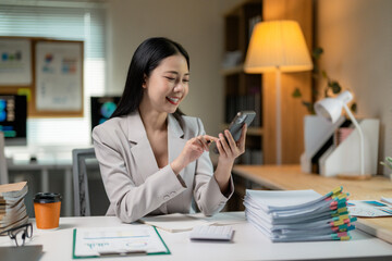Young professional woman browsing on her phone and smiling while working in her office