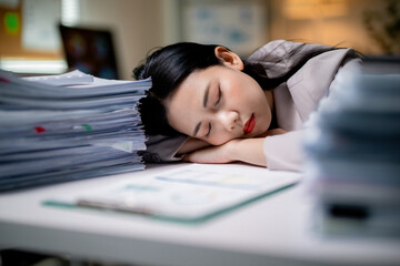 Exhausted asian professional napping beside paperwork, depicting workplace burnout and overwhelming...