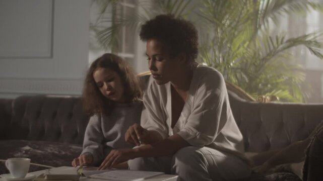 Black woman sitting on sofa teaching daughter solfeggio music