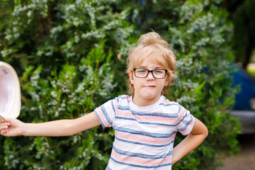 A young blonde boy with large glasses and a straw sunhat is featured in a portrait