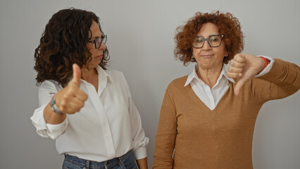 Women expressing different opinions with thumbs up and down against a white wall, showcasing...