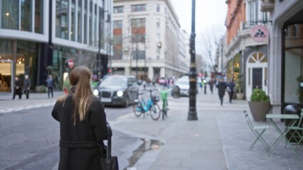 Woman walking on a busy london street during winter with blurred cars, pedestrians, and buildings...