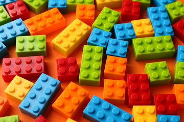 Fototapeta premium Construction toy. Colorful building bricks on orange background, closeup