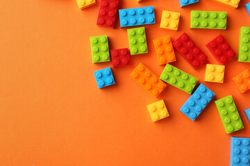 Obraz premium Construction toy. Colorful building bricks on orange background, flat lay with space for text