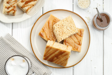 Delicious caramel puffed rice bars served on white wooden table, flat lay