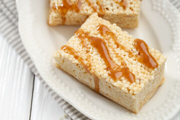 Delicious caramel puffed rice bars on white wooden table, closeup
