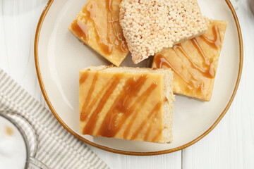 Delicious caramel puffed rice bars served on white wooden table, flat lay