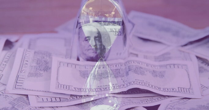 Image of hourglass over dollar banknotes