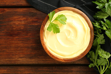 Delicious mayonnaise sauce with parsley in bowl on wooden table, top view. Space for text