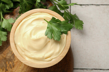 Delicious mayonnaise sauce with parsley in bowl on tiled table, top view. Space for text