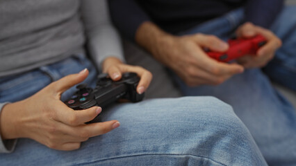 Man and woman playing video games on couch indoors, focused on holding controllers, showcasing leisure and teamwork in cozy home setting with casual attire.