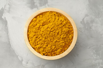 Turmeric powder in bowl on light grey table, top view
