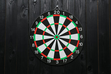 One dart board hanging on black wooden background
