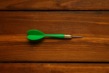 Green dart arrow on wooden table, top view