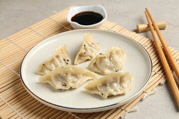 Delicious gyoza dumplings with sesame seeds served on light table, closeup
