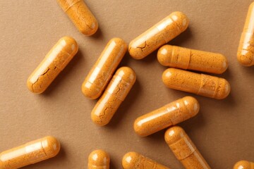 Turmeric capsules on beige background, flat lay