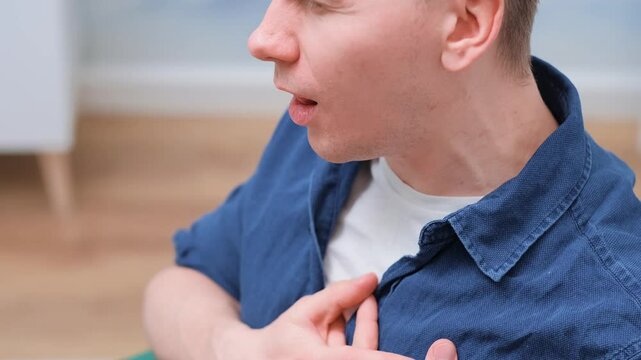 The man coughs and rubs his chest, the concept of a sick heart and pneumonia, burning of the chest.