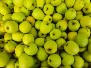 There are many green apples on the store counter. Green apple raw fruit backgrounds, natural healthy organic fresh product. Fresh green apples on the market. 