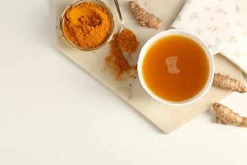 Aromatic turmeric tea, powder and rhizomes on white table, flat lay. Space for text