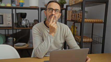 Mature man contemplating at desk in modern office environment with thoughtful expression wearing...