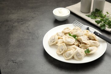 Delicious dumplings with fresh parsley served on grey table, space for text