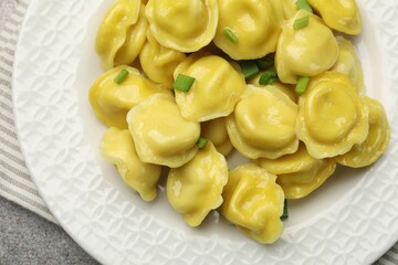 Tasty dumplings with green onion on grey textured table, top view