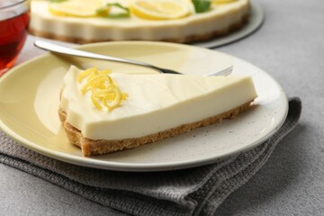 Piece of tasty lemon cheesecake on grey textured table, closeup