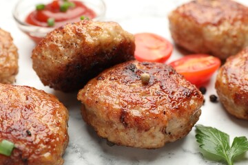 Delicious patties with sauce, cherry tomatoes and parsley on white marble table, closeup