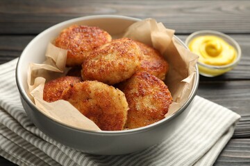 Tasty patties in bowl on wooden table, closeup