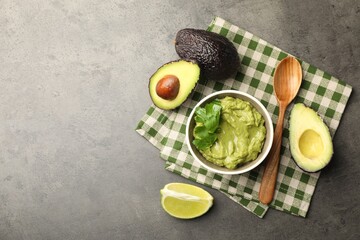 Tasty avocado dip in bowl, parsley and fruits on grey table, flat lay. Space for text