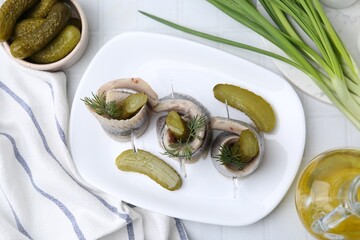Delicious herring rolls with pickles and dill on light table, flat lay
