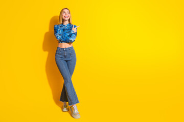 Young fashionable woman in stylish attire posing against a vibrant yellow background with a cheerful expression