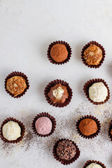 Homemade chocolate truffles with dark chocolate ganache covered with pink powder, waffle crumbles, gold flakes, coconut and nuts