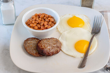 fried eggs with sausage patty  and baked beans