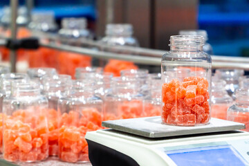 Jar of nutritional gummy bears on the scale on the factory packaging process