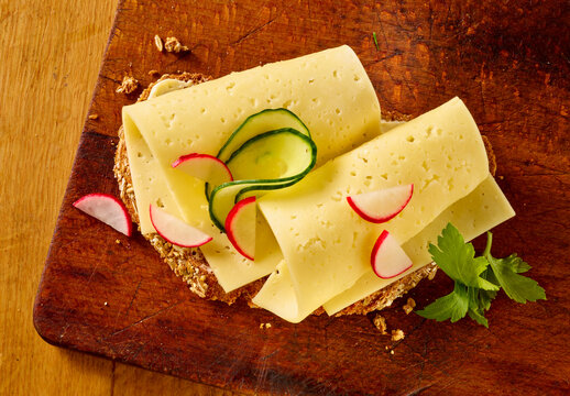 Tilsiter auf Vollkornbrot auf dunklem Holzbrett, k&auml;sebrot, Topshot, K&auml;se, Abendbrot,
