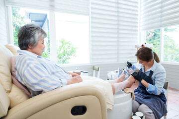 Asian senior woman enjoying a relaxing pedicure session at a luxury nail spa. Professional nail...