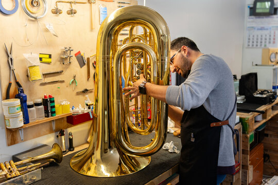 Instrument repairman carefully restoring a tuba in his workshop