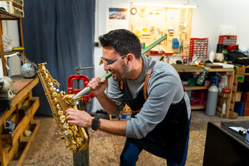 Instrument repairman straightening saxophone neck in workshop