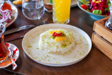 Delicious rich Traditional Turkish breakfast include tomatoes, cucumbers, cheese, butter, eggs, honey, bread, bagels, olives and tea cups.